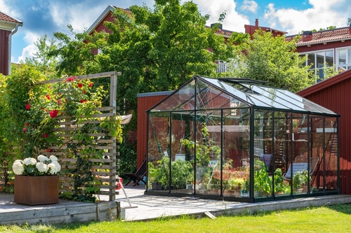 Billede af glasdrivhus på stenterasse i have