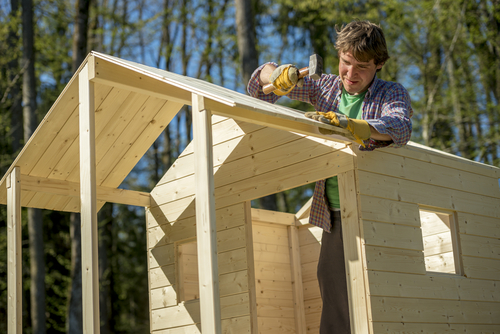 Et billede af en mand der bygger et trælegehus